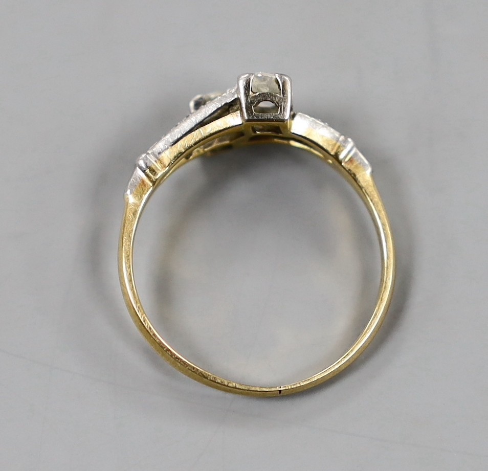 An 18ct, plat and two stone diamond crossover ring, with diamond set shoulders, size N/O, gross weight 2.7 grams.